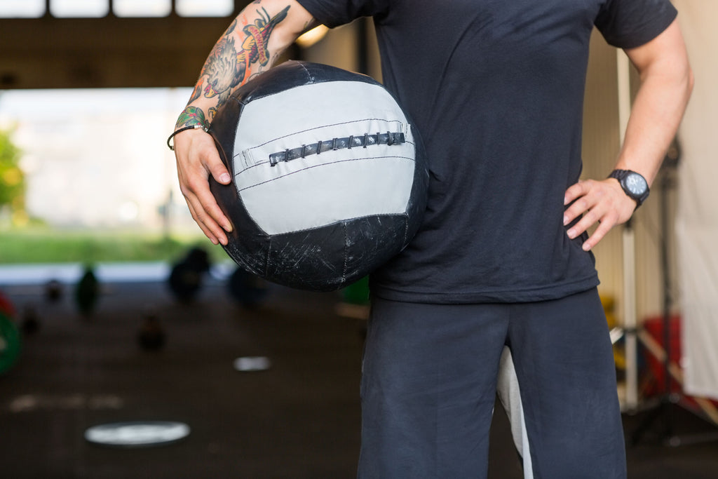 Fit man holding a medicine ball with weight lifting equipment in the background