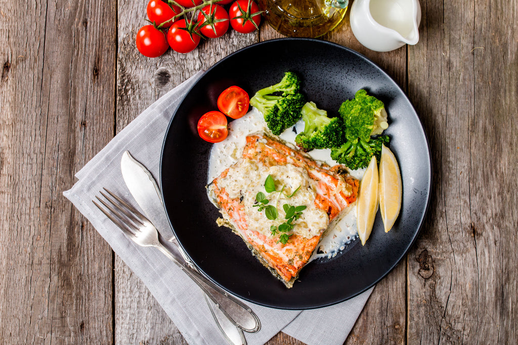 Salmon and vegetables on plate on a wooden table.