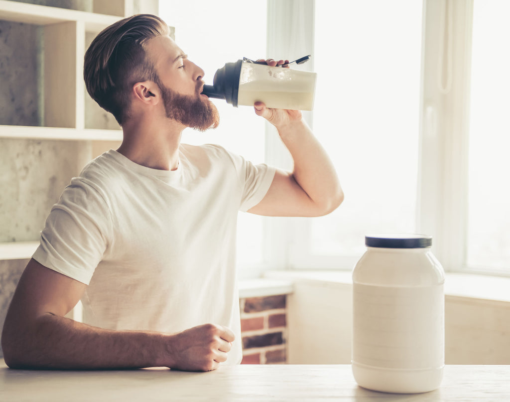 Bearded man drinking protein shake with added supplements